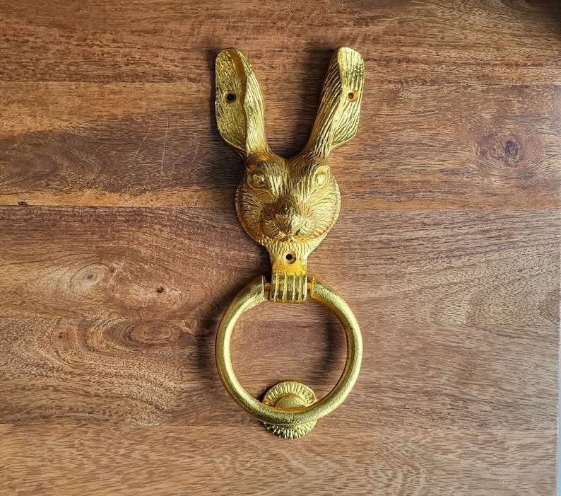 Golden brass rabbit door knocker home decor on a wooden background.