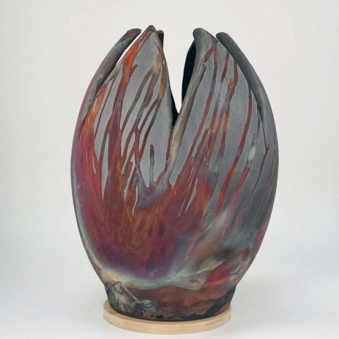Large, multi-colored flower vase; raku firing; unique design; wooden base.
