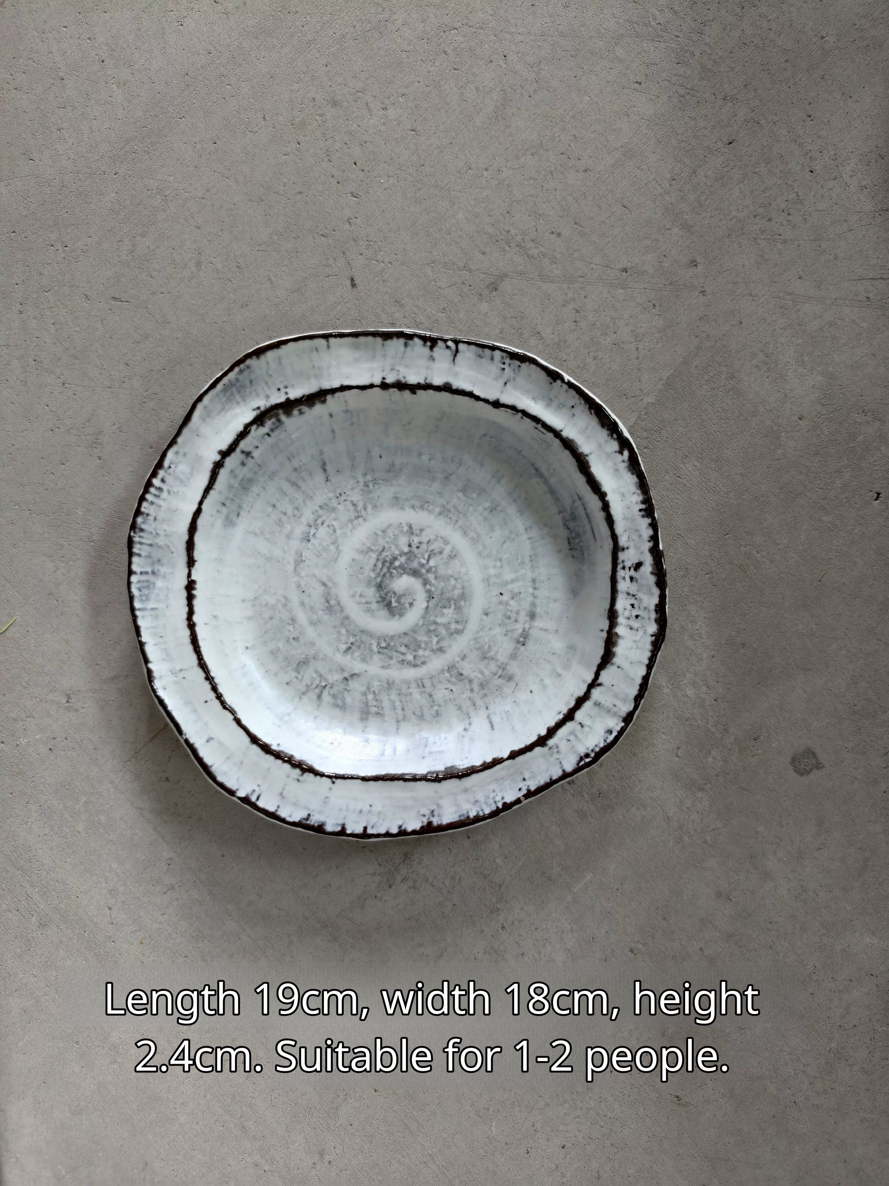 Oval ceramic plate in white with black rim, spiral pattern, 19x18x2.4cm, for 1-2 servings.