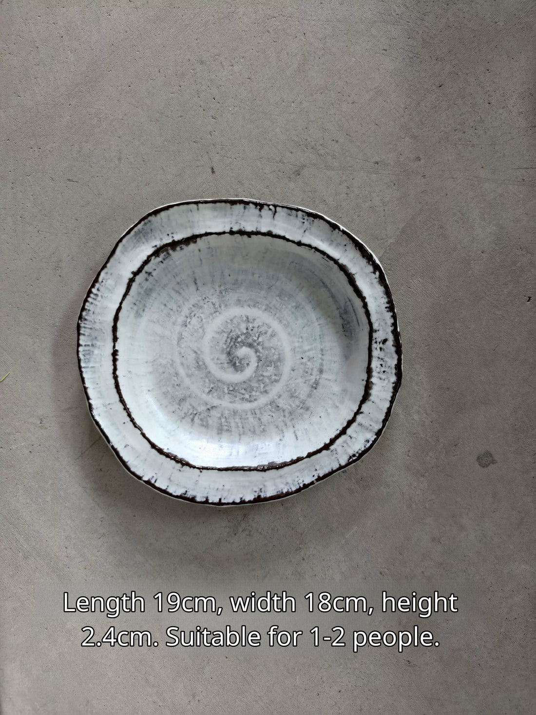 Oval ceramic plate in white with black rim, spiral pattern, 19x18x2.4cm, for 1-2 servings.