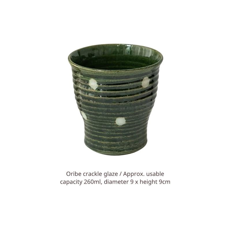 Studio shot of a dark green ceramic Yunomi cup with white spots, text description below.