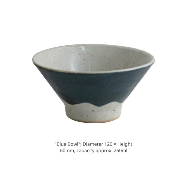 Product shot of a small blue ceramic bowl with an uneven glaze line.