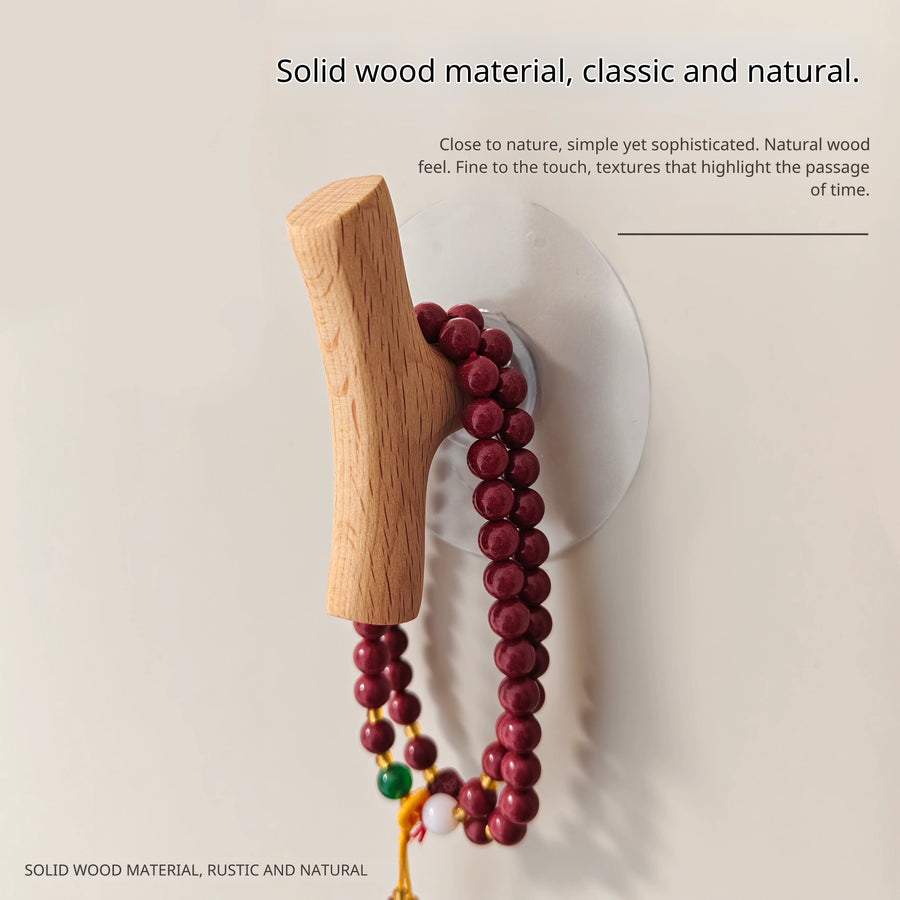 Light wood branch hook holding a string of red wooden prayer beads against a light wood background.