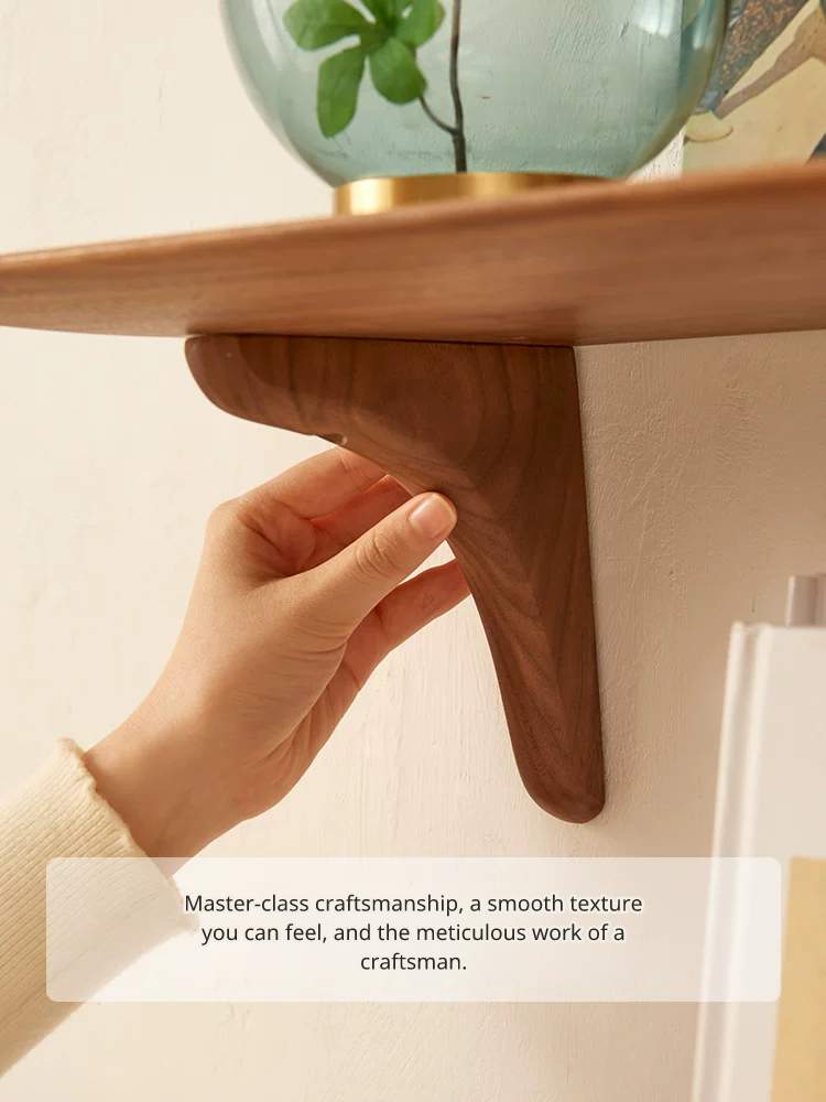 Hand touching the smooth, polished wood surface of a floating shelf bracket.