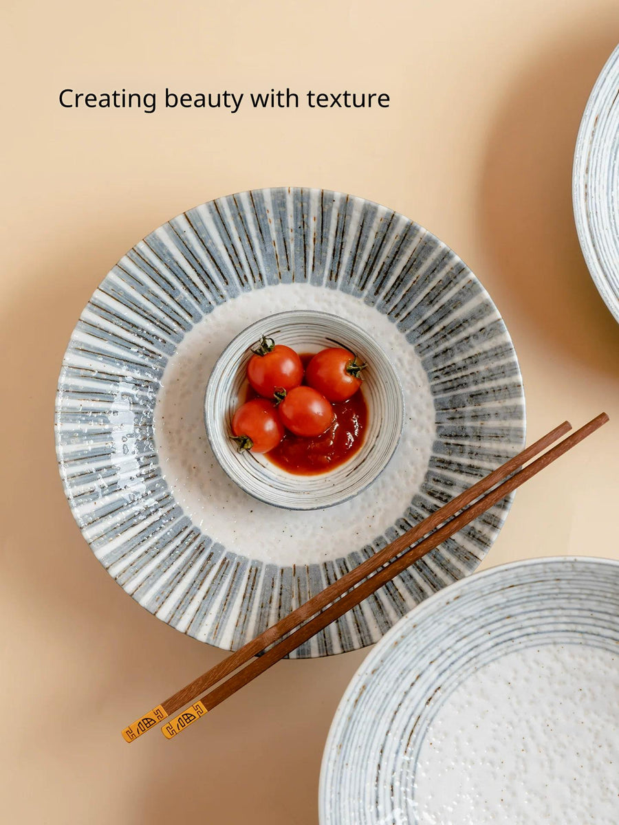 Two stacked Japanese style ceramic plates with radial grey-blue stripes, one holding cherry tomatoes.