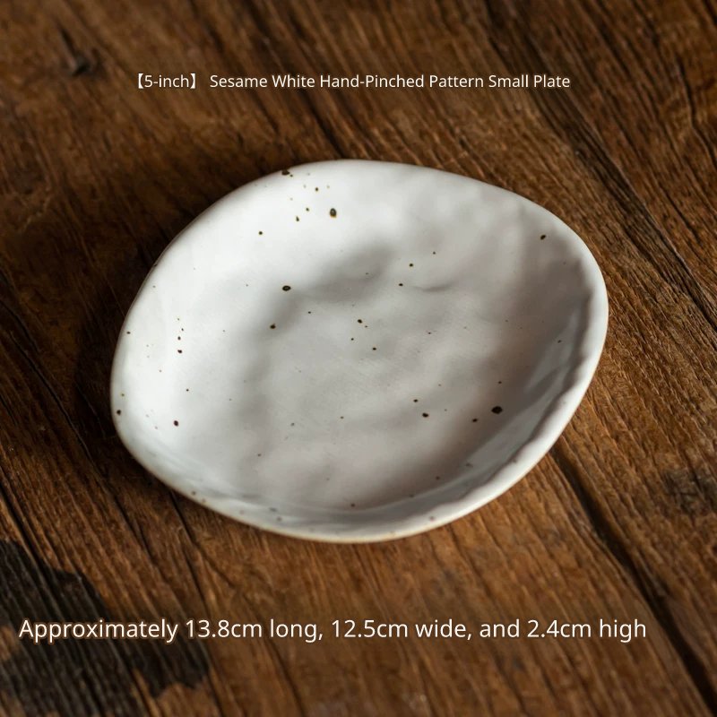 A medium, oval, speckled white ceramic plate, slightly smaller than the previous one, on wood.