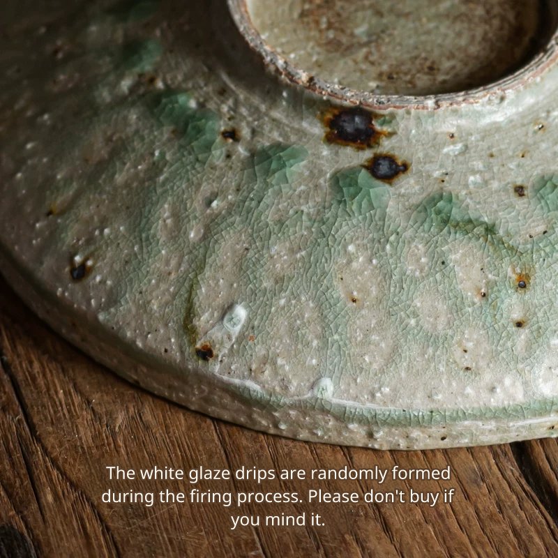 Detailed view of the side and crackled glaze of a rustic ceramic plate showing white flow marks.