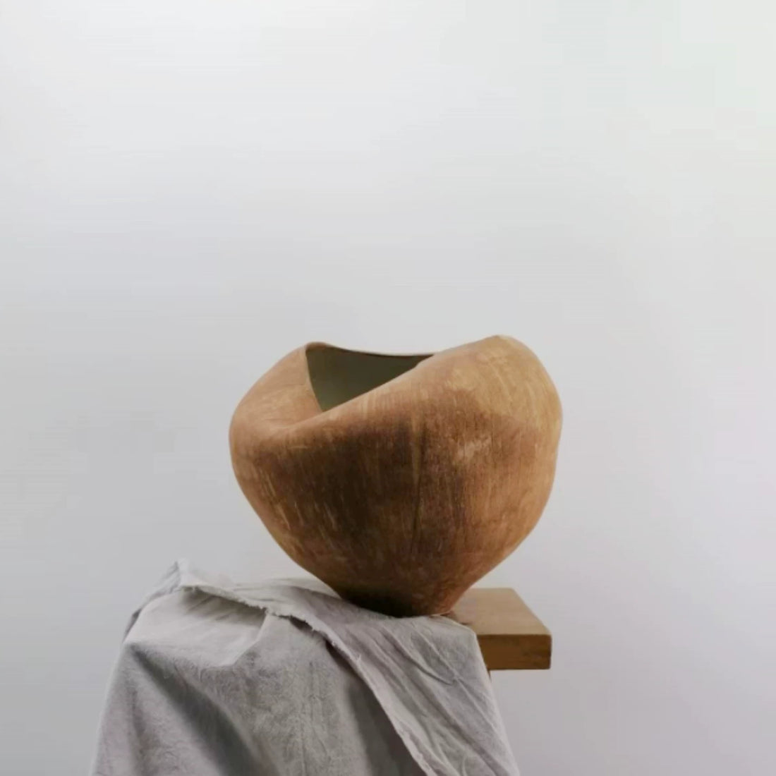 A white ceramic vase with a unique, sculptural folded design and a textured matte finish.