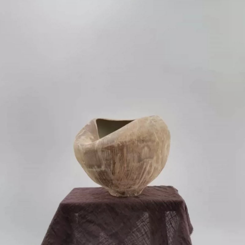 A sculptural handmade ceramic vase with a unique folded, ruffled design in a neutral beige tone.