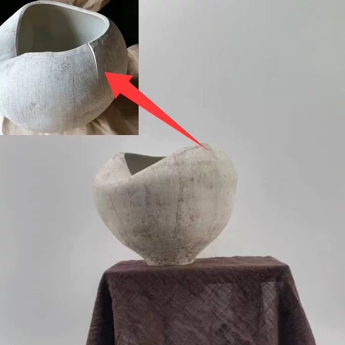 A handmade ceramic vase featuring a unique, sculptural folded design with a textured white finish.
