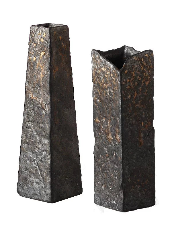A handmade ceramic vase with a textured stone finish and a subtle metallic glaze.