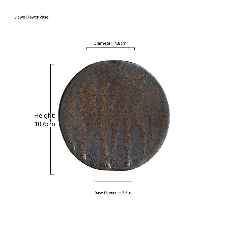 A handmade ceramic vase with a rustic stone texture and subtle metallic glaze on a neutral surface.