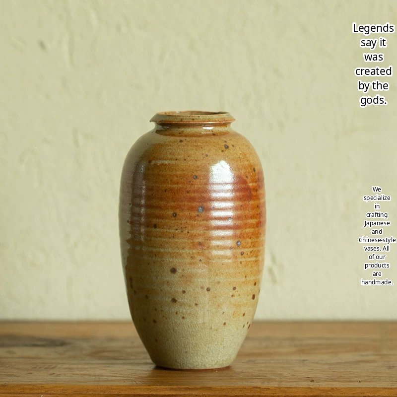 A handmade ceramic vase with a unique mottled dark glaze and a minimalist cylindrical shape.