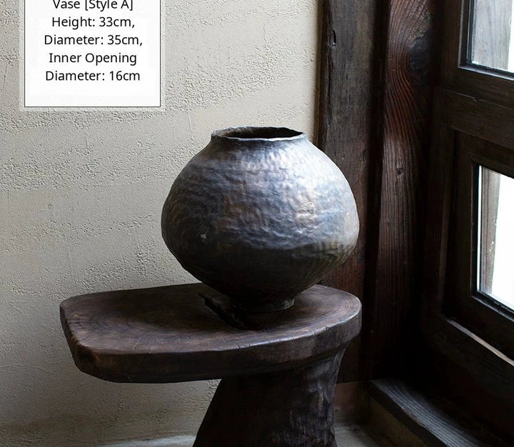 A black glossy handmade ceramic vase with a unique artisan shape on a dark surface.