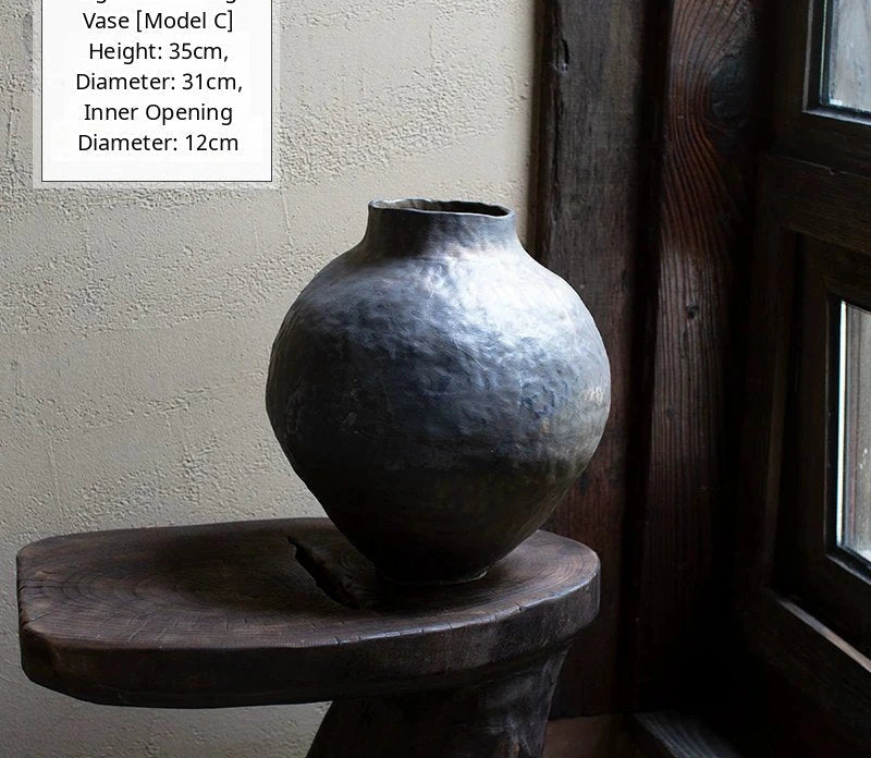 A handmade black glossy ceramic vase with an organic, asymmetric shape on a neutral background.