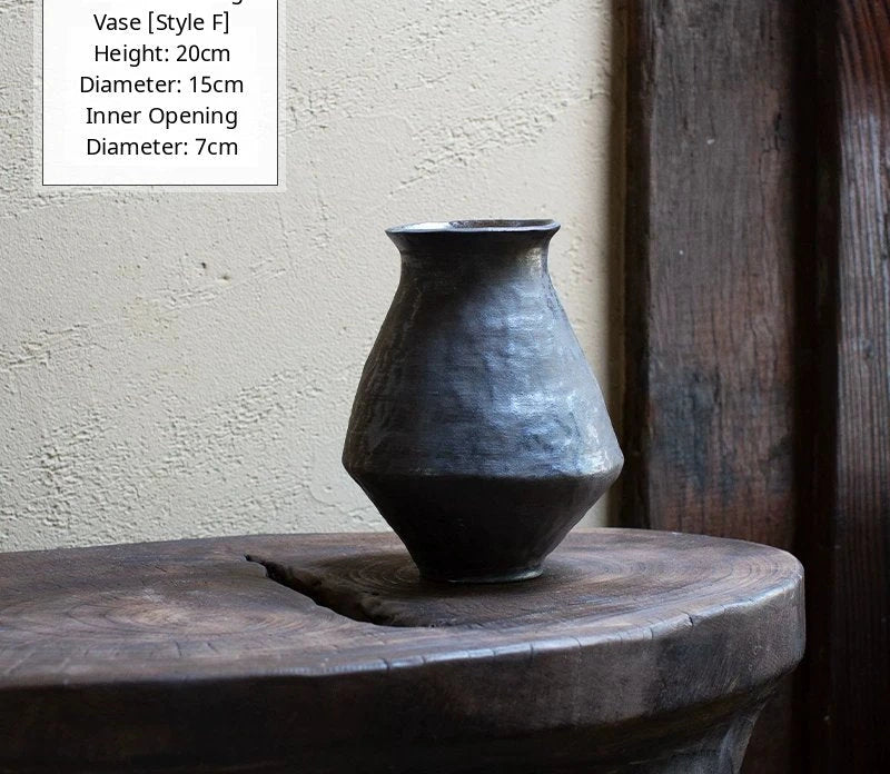 A black glossy handmade ceramic vase with an organic, asymmetric shape on a neutral background.