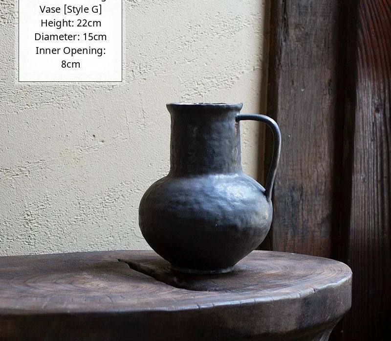 A black glossy ceramic vase with a unique, textured, handmade silhouette on a neutral background.