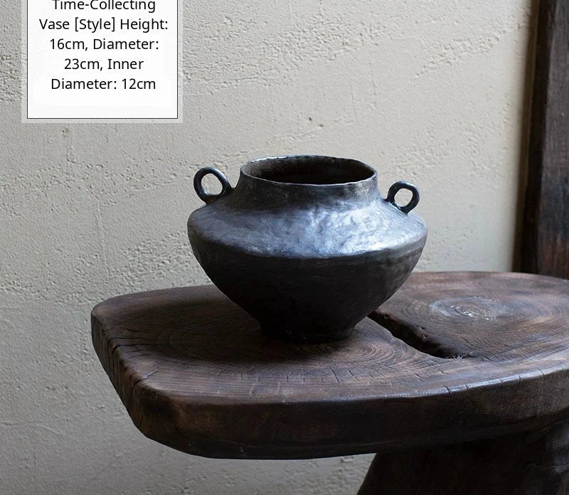 A black glossy handmade ceramic vase with a unique artisan shape, set against a plain background.