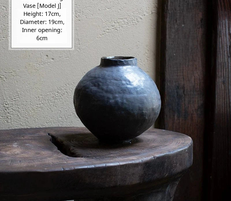A handmade black glossy ceramic vase with a unique artisan shape and smooth reflective finish.