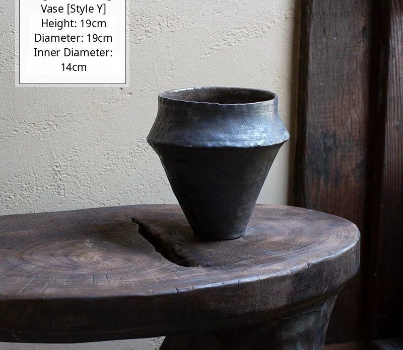 A handmade black glossy ceramic vase with a unique artisan shape and smooth reflective finish.