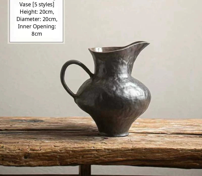 A black glossy handmade ceramic vase featuring an irregular, sculptural silhouette.