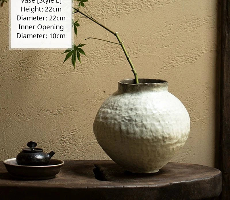 A black glossy handmade ceramic vase with a unique artisan shape, set against a plain background.