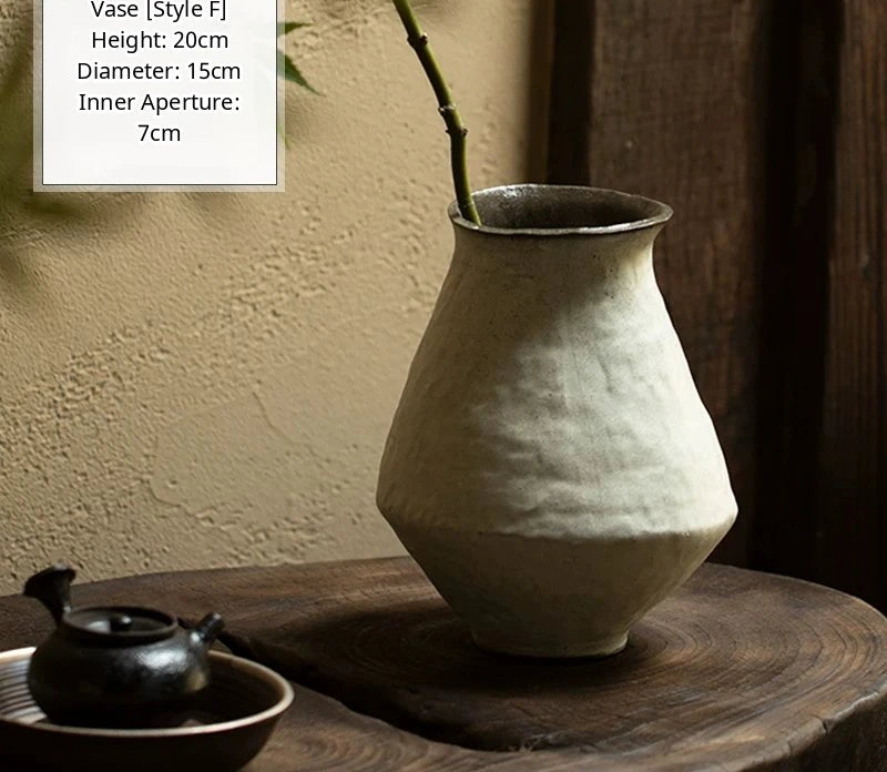 A black glossy handmade ceramic vase with an irregular, bulbous silhouette rests on a flat surface.