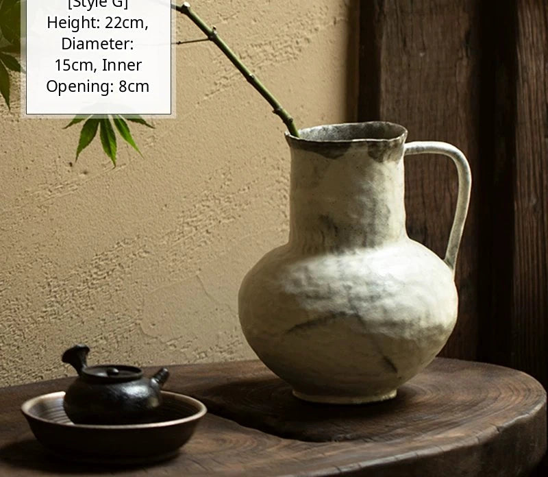 A handmade black glossy ceramic vase with an organic, asymmetric shape resting on a textured surface.
