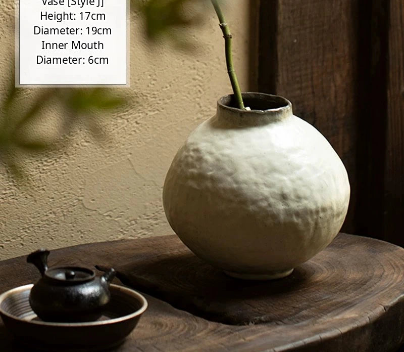 A black glossy handmade ceramic vase with an irregular, curved artisan shape.
