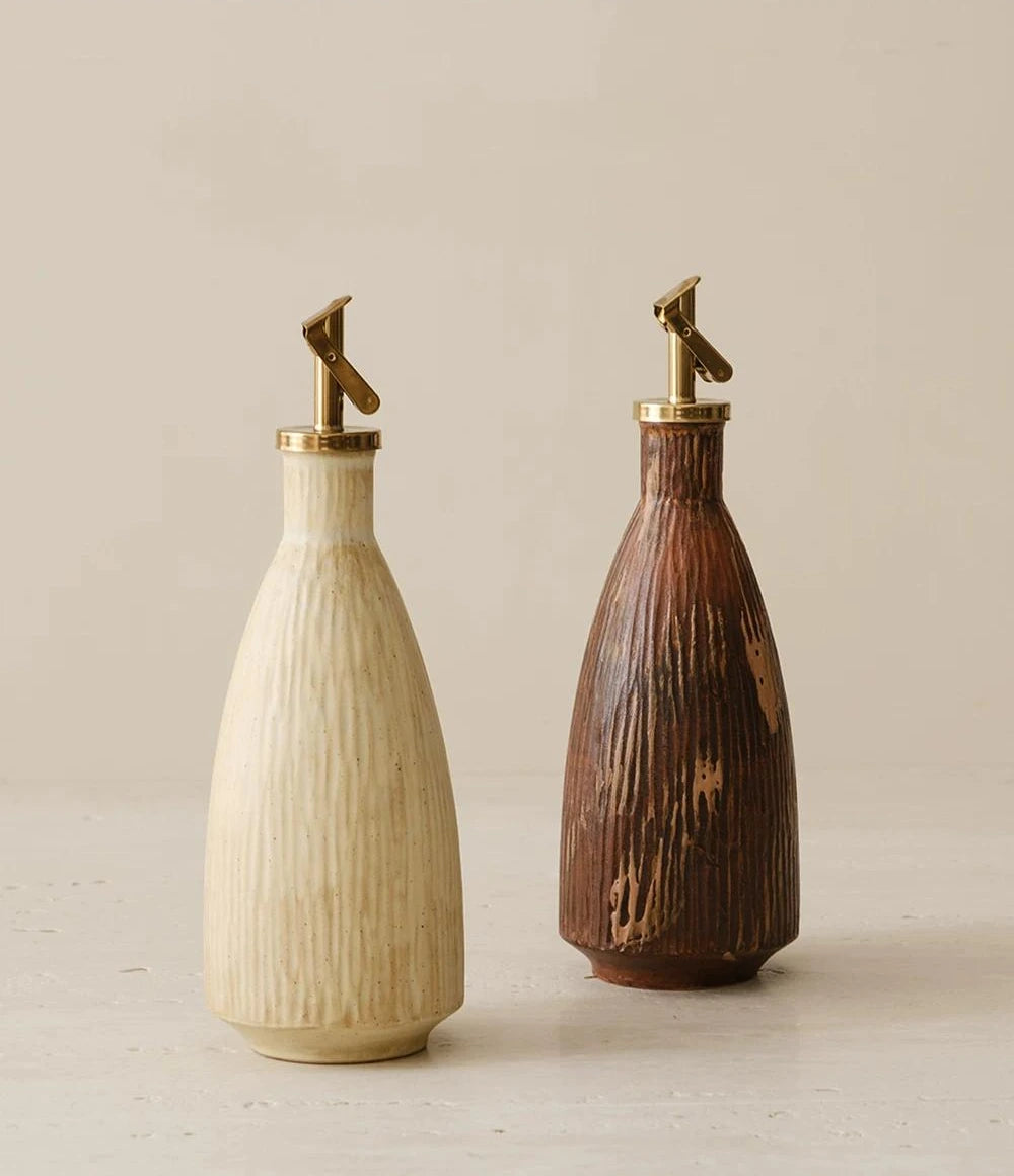 Textured ceramic oil dispenser with a metallic automatic flip spout and a minimalist glazed finish.