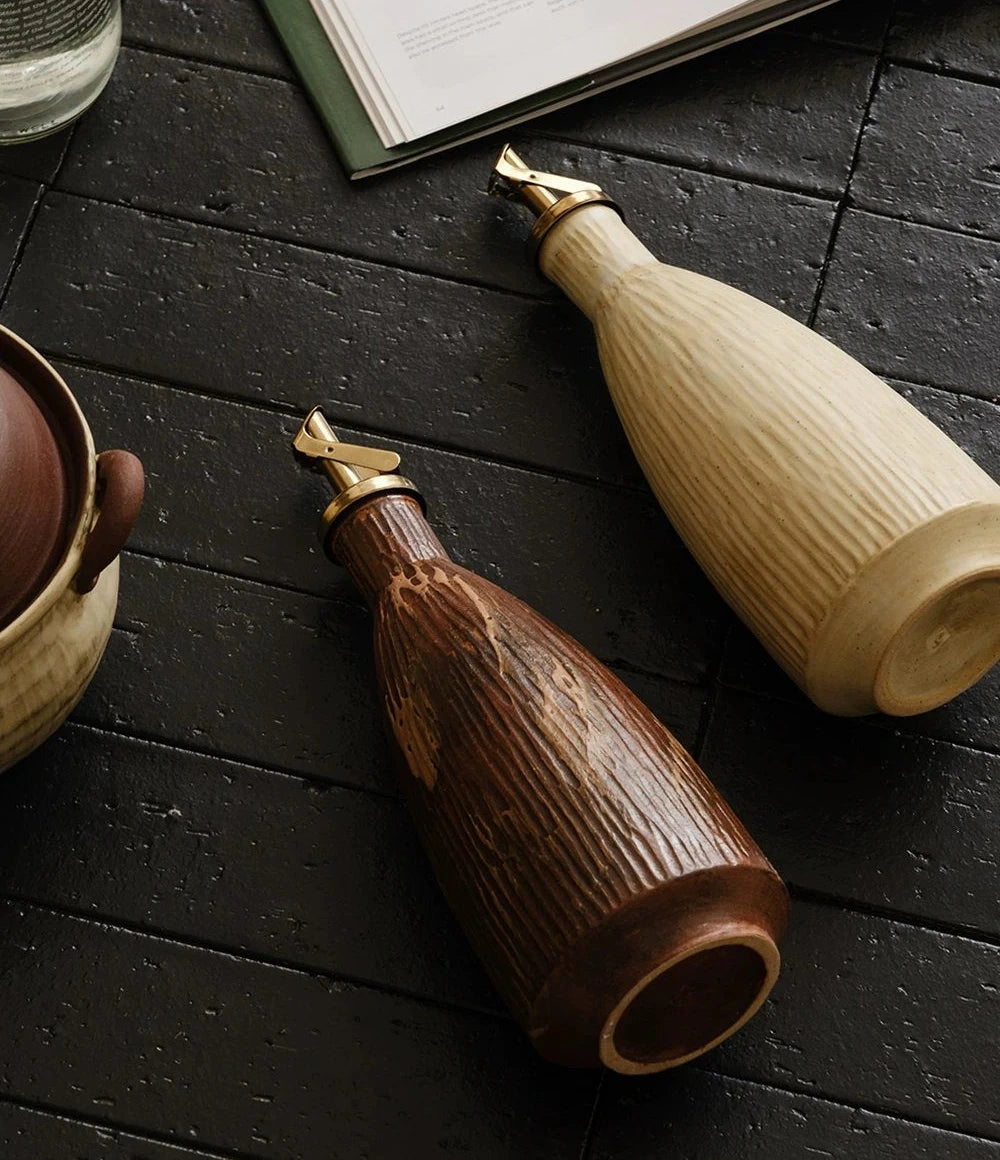 White ceramic oil dispenser with an automatic flip metal spout and textured glaze.