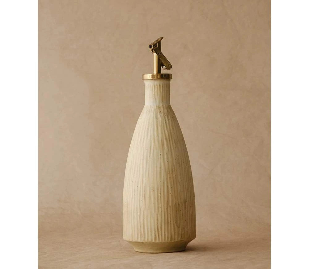 A rustic ceramic oil dispenser with a textured glaze and a metallic flip spout on a dark background.
