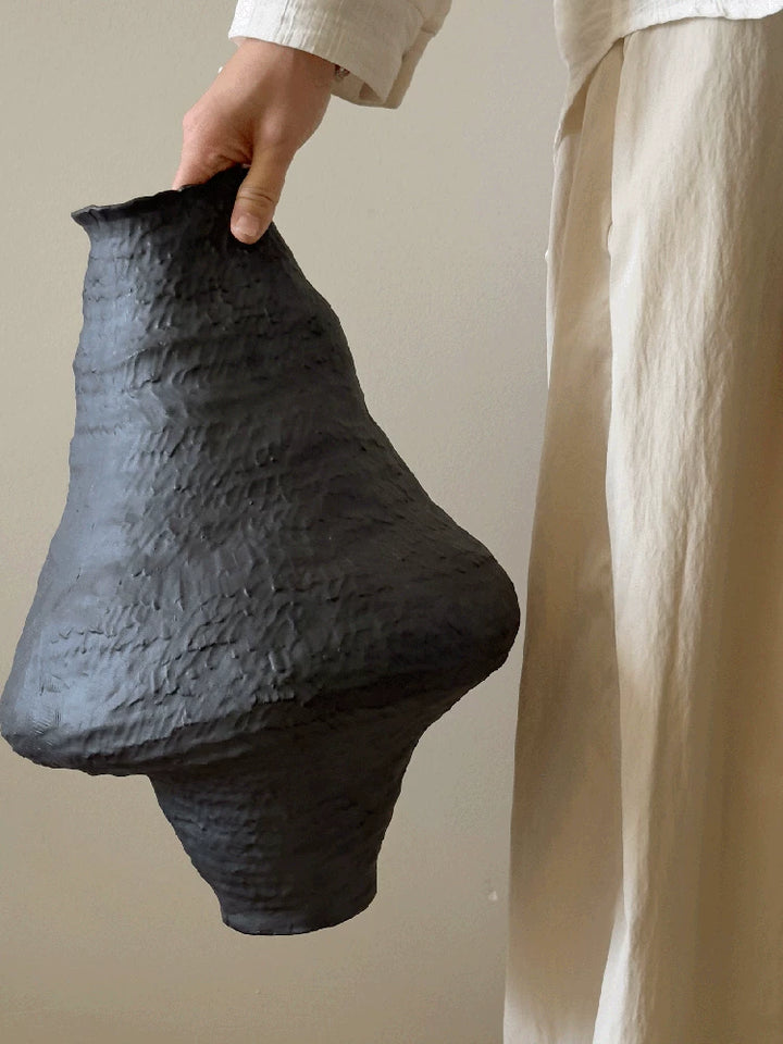 Handmade black ceramic vase with a textured clay finish and an artistic sculptural design.