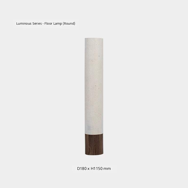 A white paper floor lamp with a dark wooden tripod base emits a warm glow in a minimalist room.