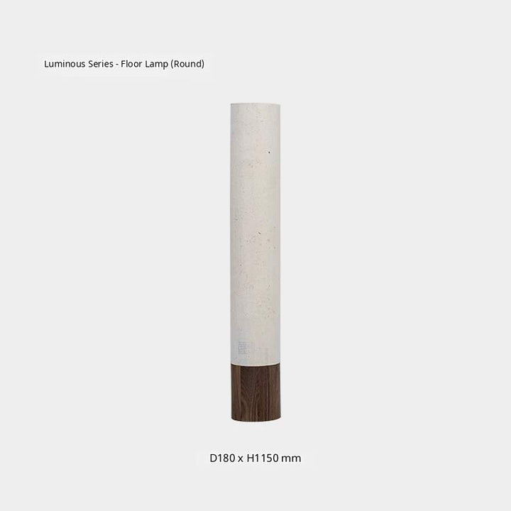 A white paper floor lamp with a dark wooden tripod base emits a warm glow in a minimalist room.