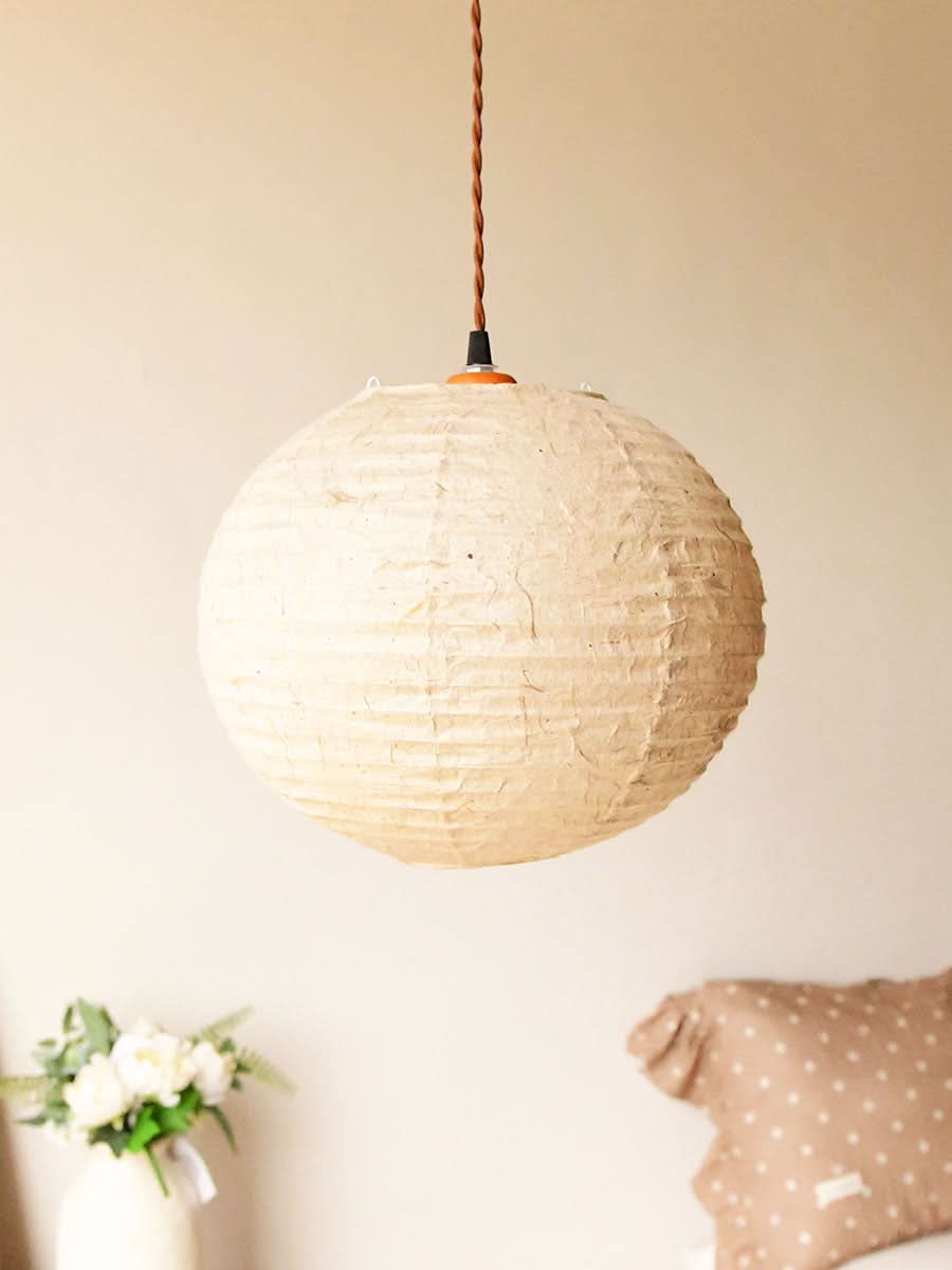 Natural beige handmade paper lampshade, textured, suspended from brown cord. Home decor accent.