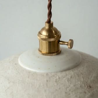 Textured white paper mache lamp shade with brass hardware, perfect home decor.