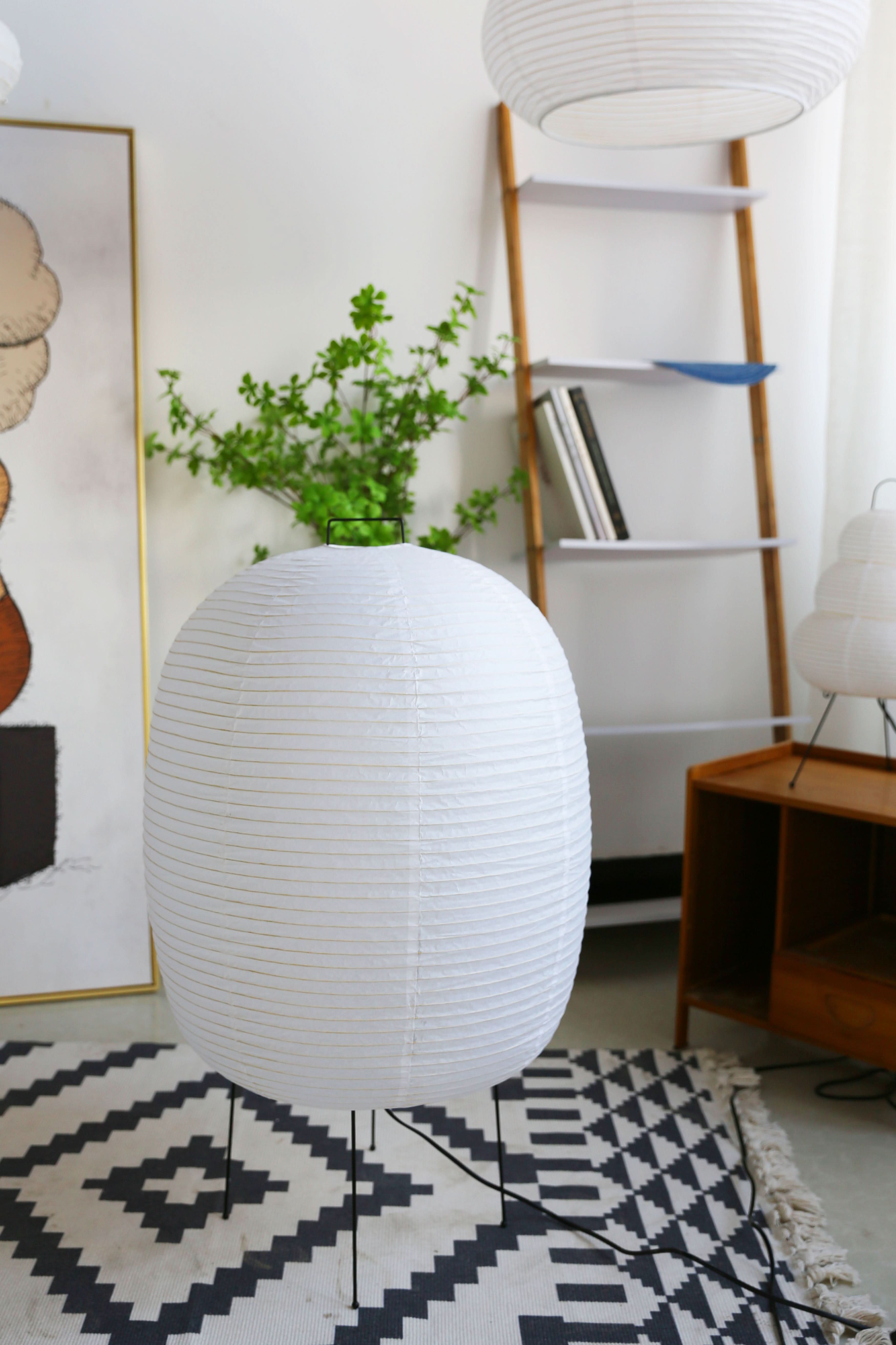 White spherical paper floor lamp on black legs, accenting modern home decor.