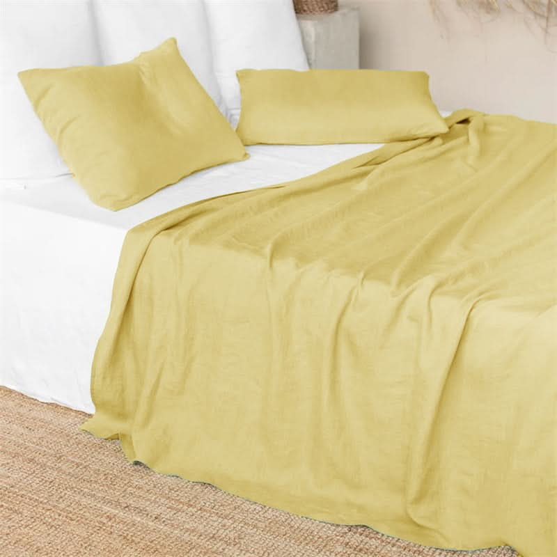 Yellow linen bed sheets on a white bed, with matching pillowcases.