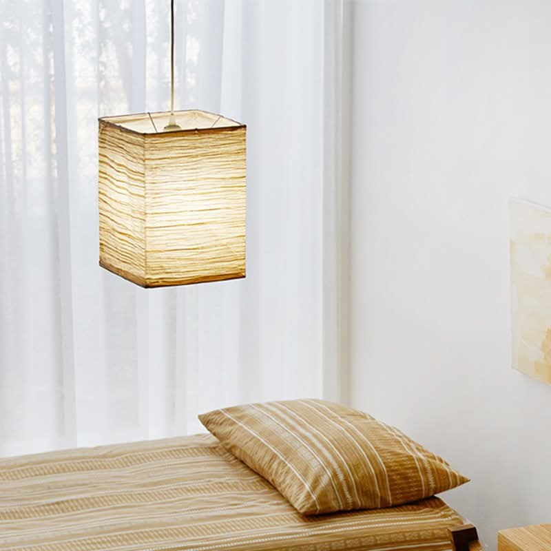Warm glow from squared paper lampshade in a minimalist bedroom setting.