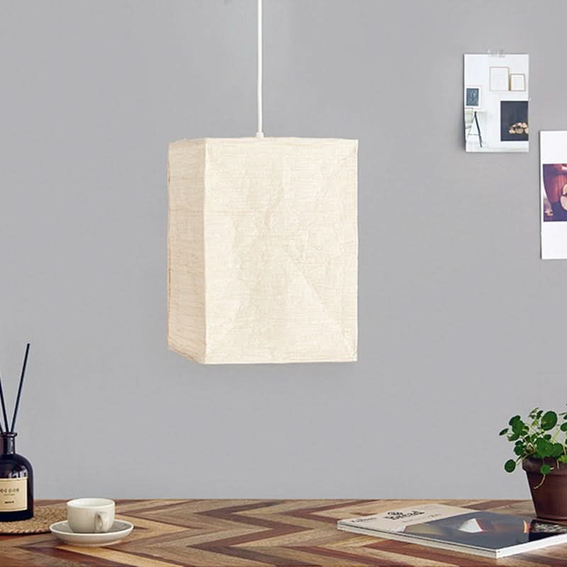 Cream Squared Paper Lampshade hanging in a modern home setting, on a desk with decor.