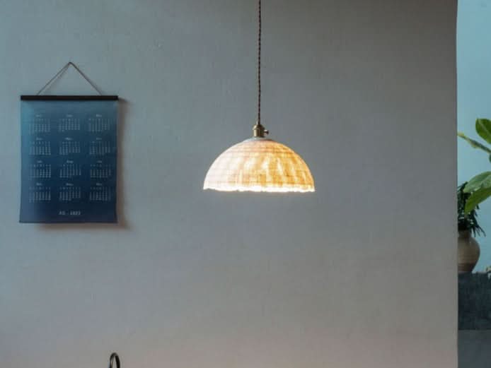 Natural fiber paper mache lamp shade in warm, neutral tones, illuminating a modern home decor space.