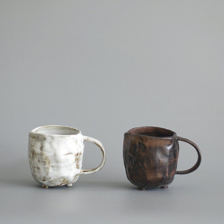 Two stoneware mugs, one white and one brown, displayed on a gray background.