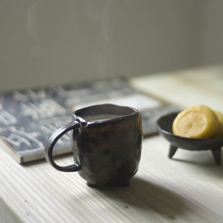 Steaming dark brown stoneware mug from the 2X1 Stoneware Mug Set with cookies on the side.