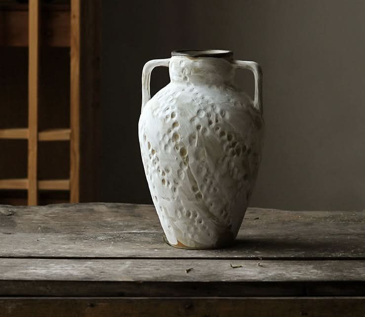 Textured white ceramic Wabi-sabi vase with two handles on a rustic wooden table.