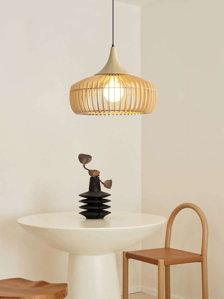 Natural wood light fixture with slats, pendant light over a white table with decorative vase.