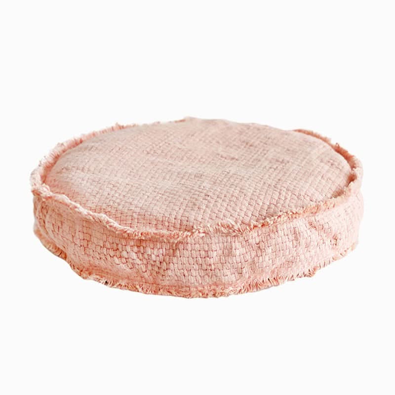 Pink textured floor cushion with frayed edge, washable and customizable for home decor.