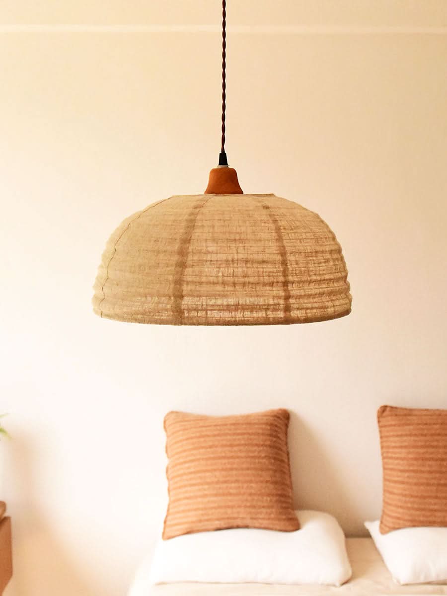 Natural hemp fabric dome lamp shade with earthy tones, hanging above pillows in a warm home decor setting.