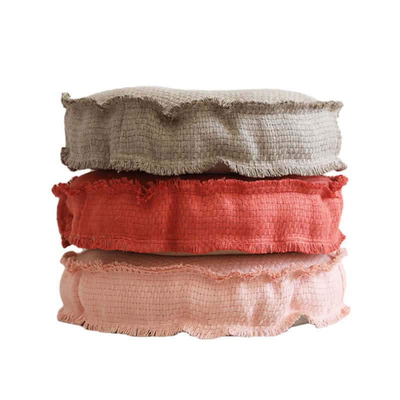 Three customizable textured floor cushions in grey, coral, and pink, with fringed edges.