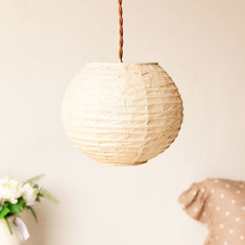 Natural cream handmade paper lampshade hanging from a brown cord, home decor accent.
